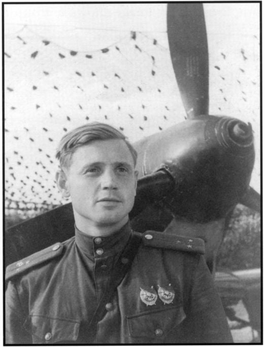 Senior Lieutenant Ivan Gorbunov, stands in front of his aircraft which is covered by lace-like camouflage netting. Gelatin Silver toned photograph by S. Kafafayon. [H98. 101/1236, text by N Virta, published Argus, 30 November 1944] [photograph]